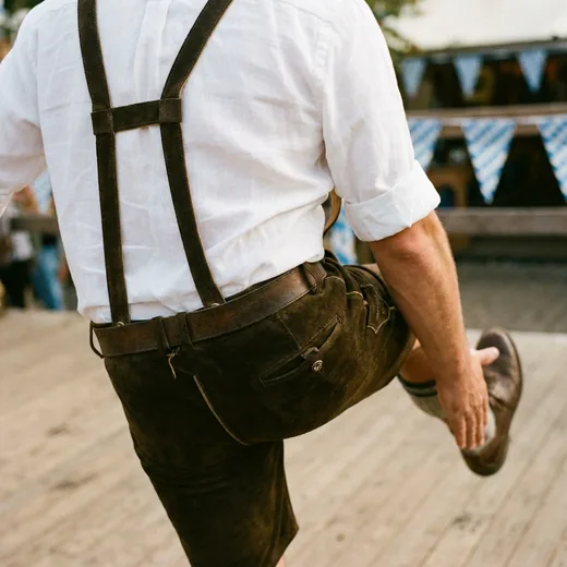 Photo: a folk dancer in lederhosen mid-jump, slapping his shoe, shirt tucked in